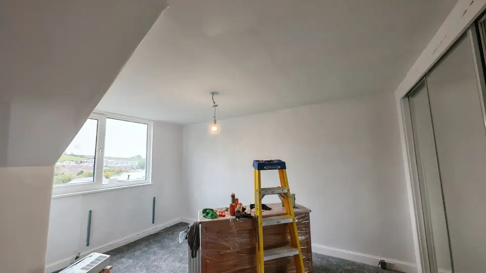 Attic bedroom with sloping ceilings, sanded smooth and painted white