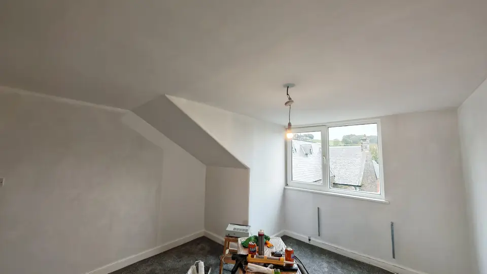 Attic bedroom window wall finished in white emulsion