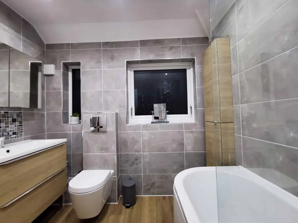Finished bathroom with grey tiling and freestanding bath