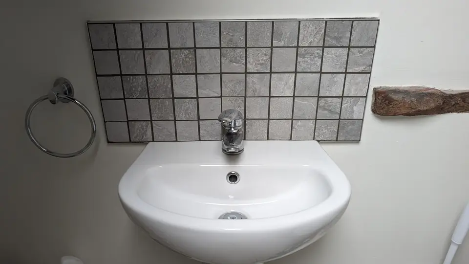 Grey mosaic tile splashback above a bathroom sink