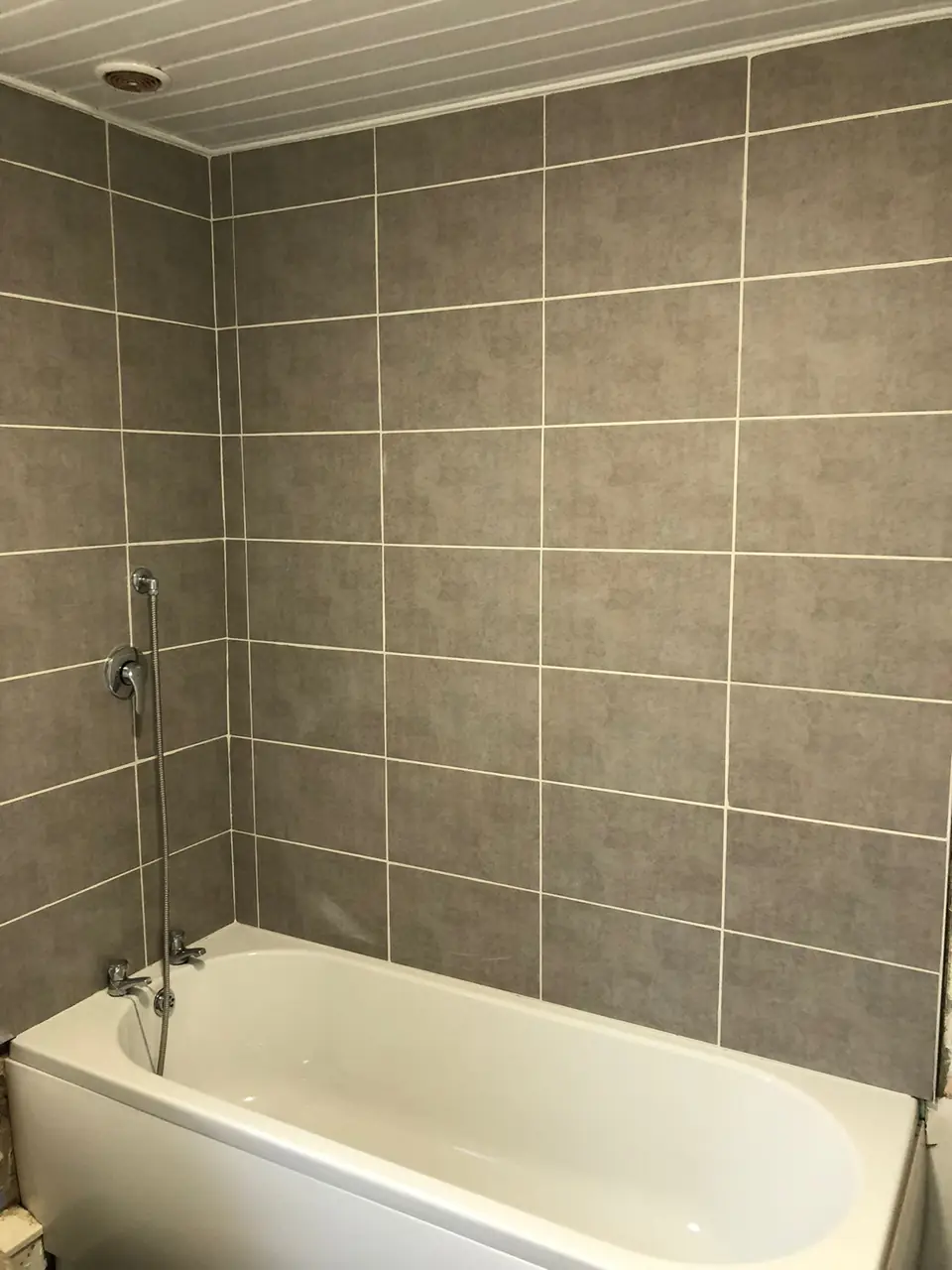 Grey tiled bath surround, floor to ceiling