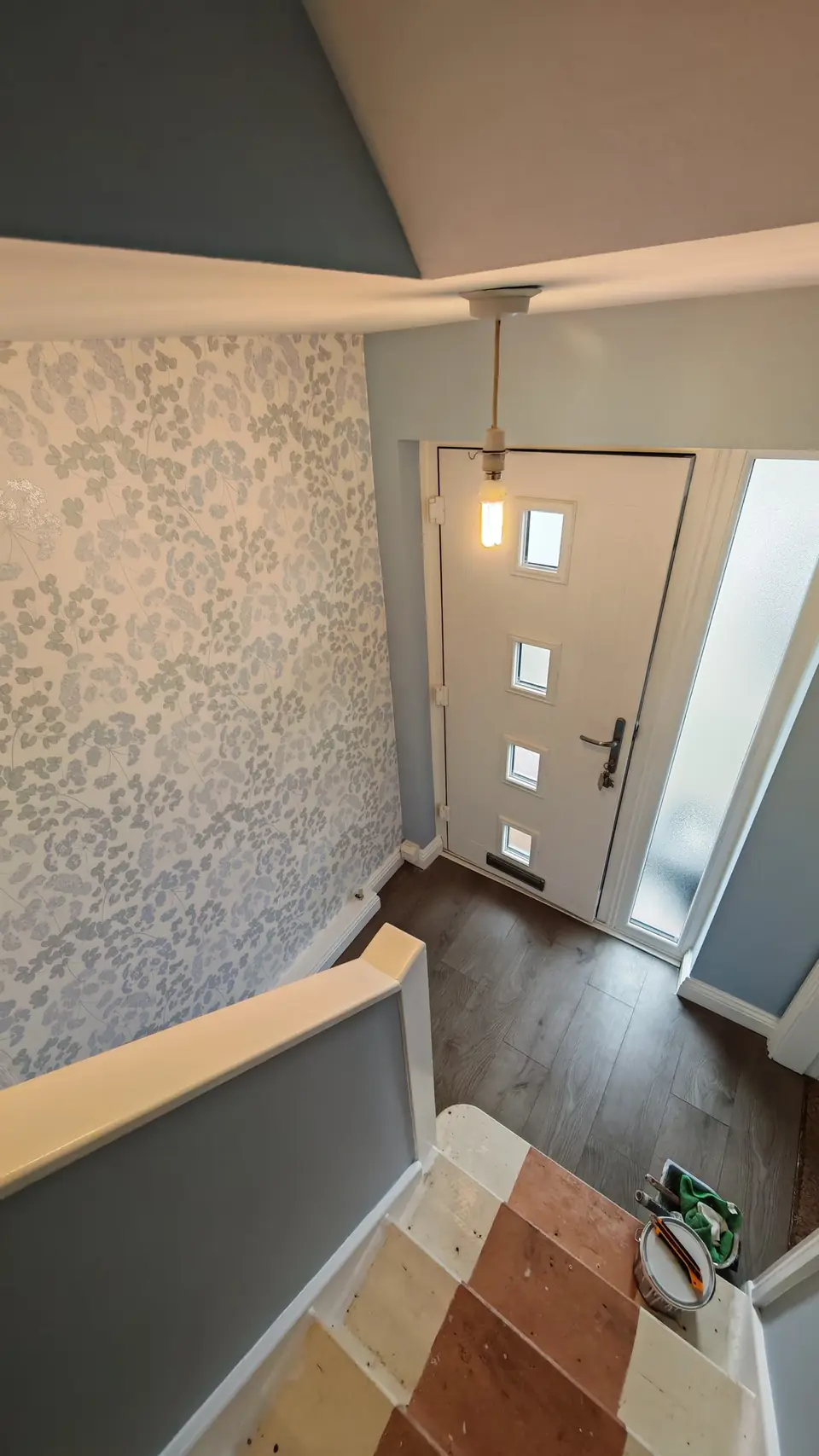 Stairs down to the front door: blue-grey walls and floral wallpaper