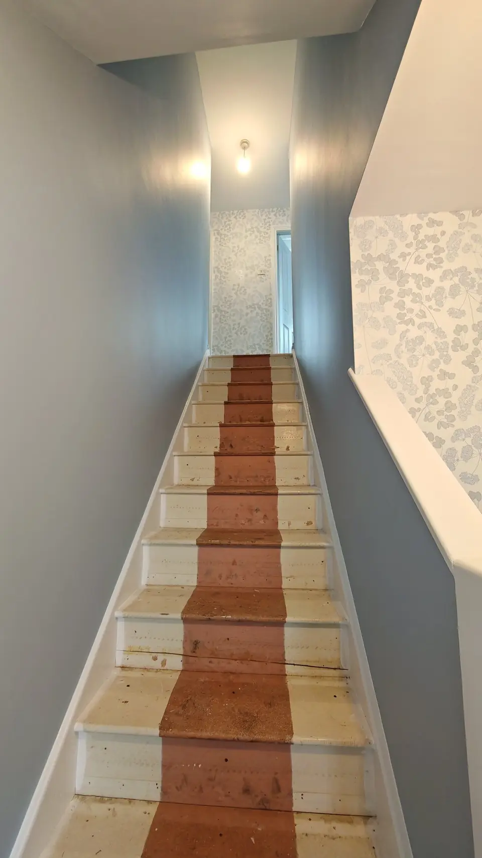 Stairs up to the wallpapered landing, walls in soft blue-grey