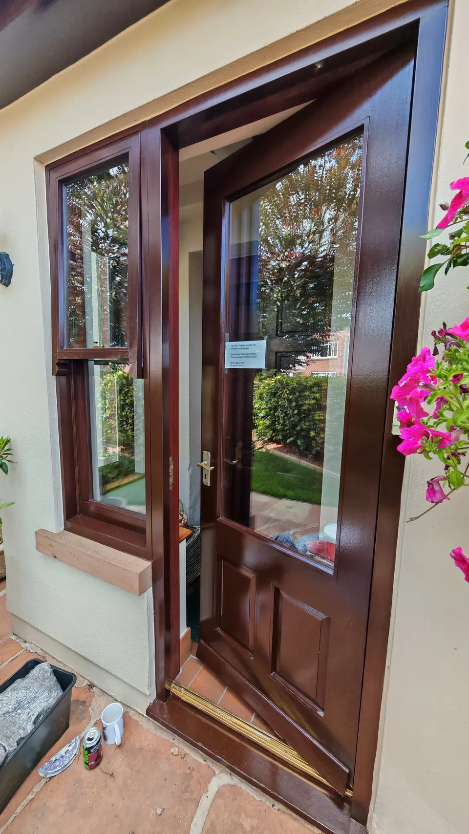 Front door and side window refinished in brown gloss, door open, pink flowers alongside