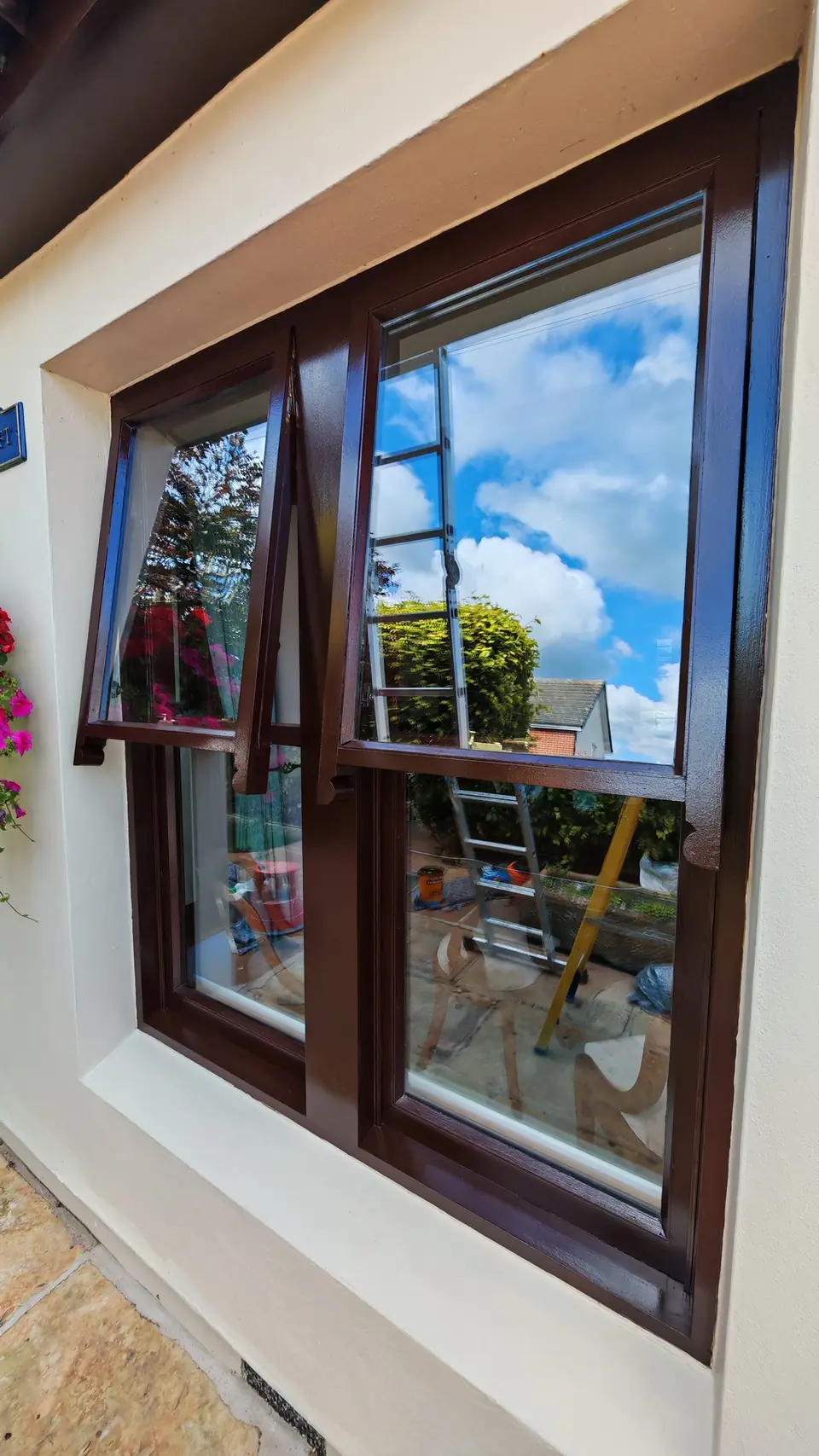 Windows refinished in brown gloss, set in cream render with flowers below