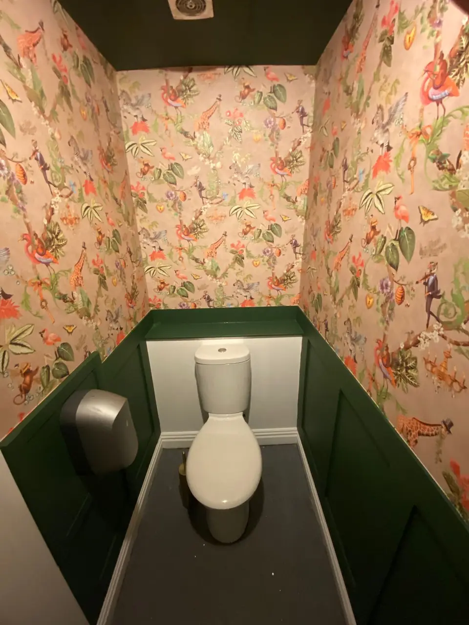 Jungle print wallpaper above wall panelling painted dark green