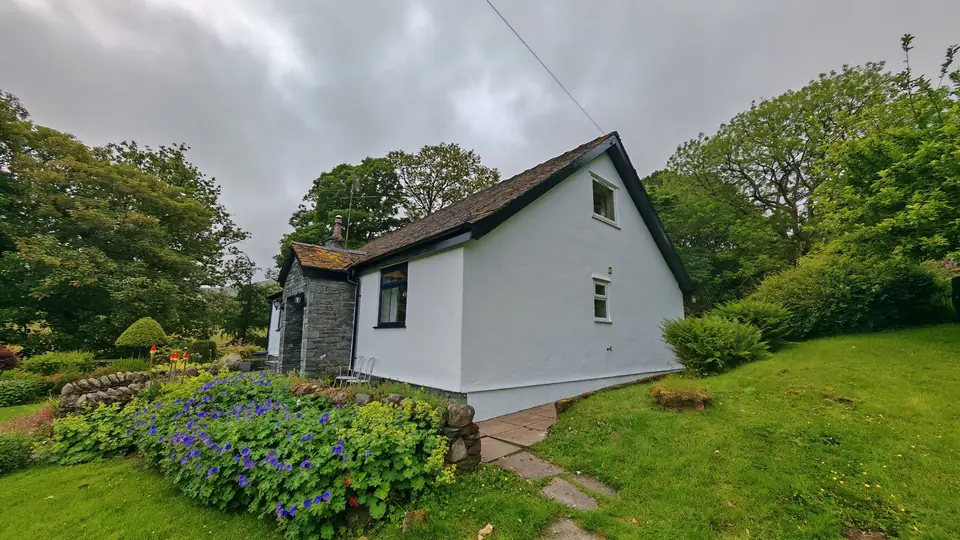 Gable end in fresh white masonry paint above the garden