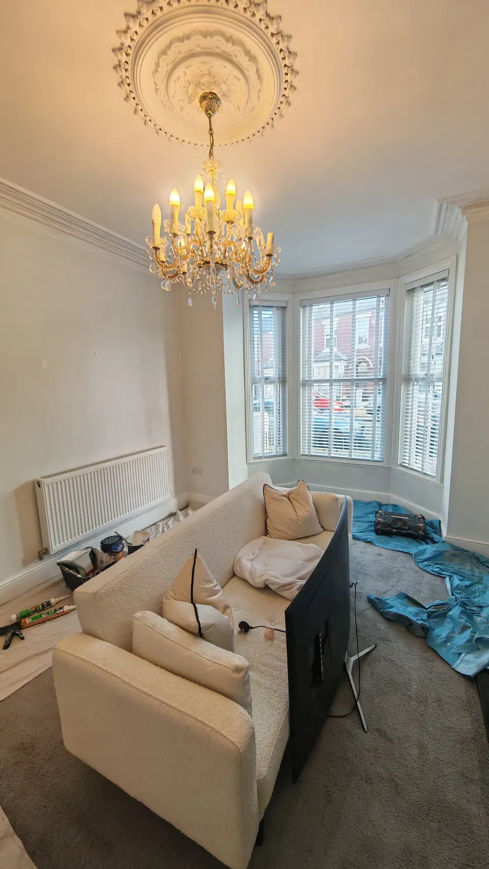 Before: cream living room with bay window, furniture under dust sheets
