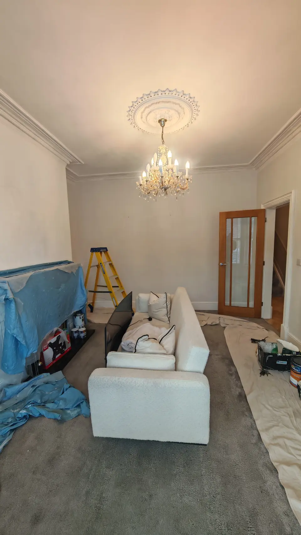 Before: cream living room towards the door, sofa covered