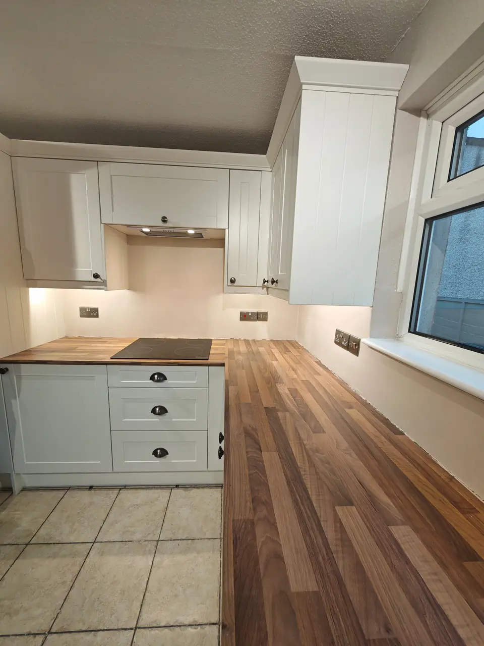 Cream shaker kitchen with a tall unit and wood-effect worktop, freshly decorated