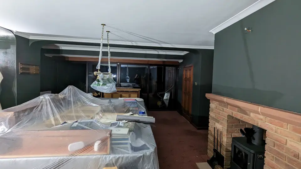 Long room being decorated in dark green with panelling, furniture protected under sheets