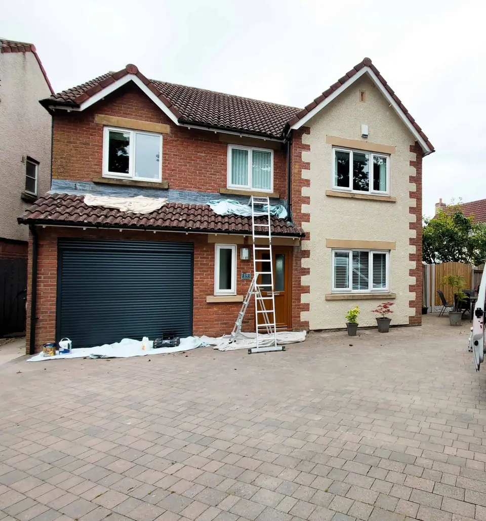 Exterior repaint in progress with ladders up on a red-brick house