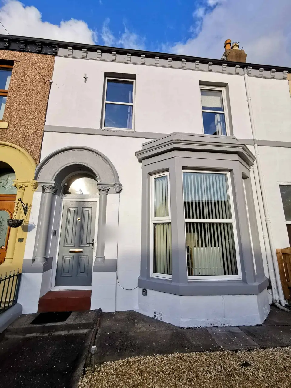 Victorian terraced house exterior painted white with grey bay window