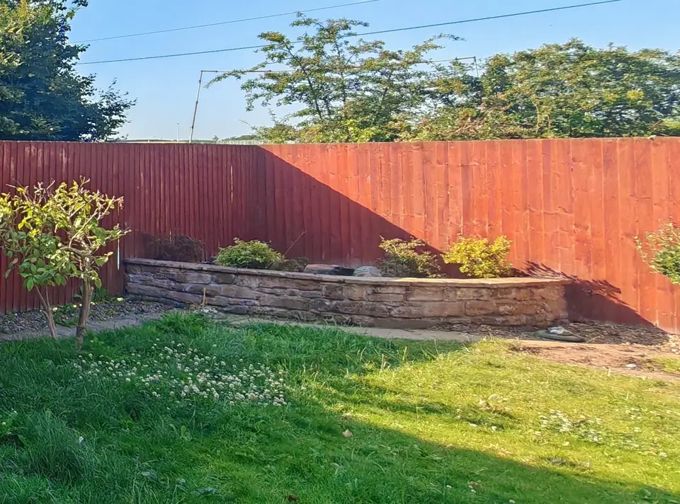 Before: orange-red fence panels behind the raised bed