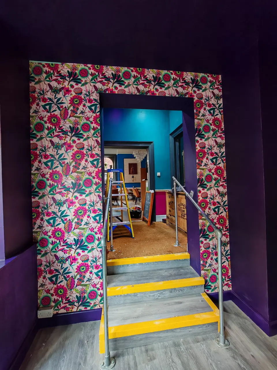 Bold floral wallpaper wrapped around an archway, set against deep purple walls