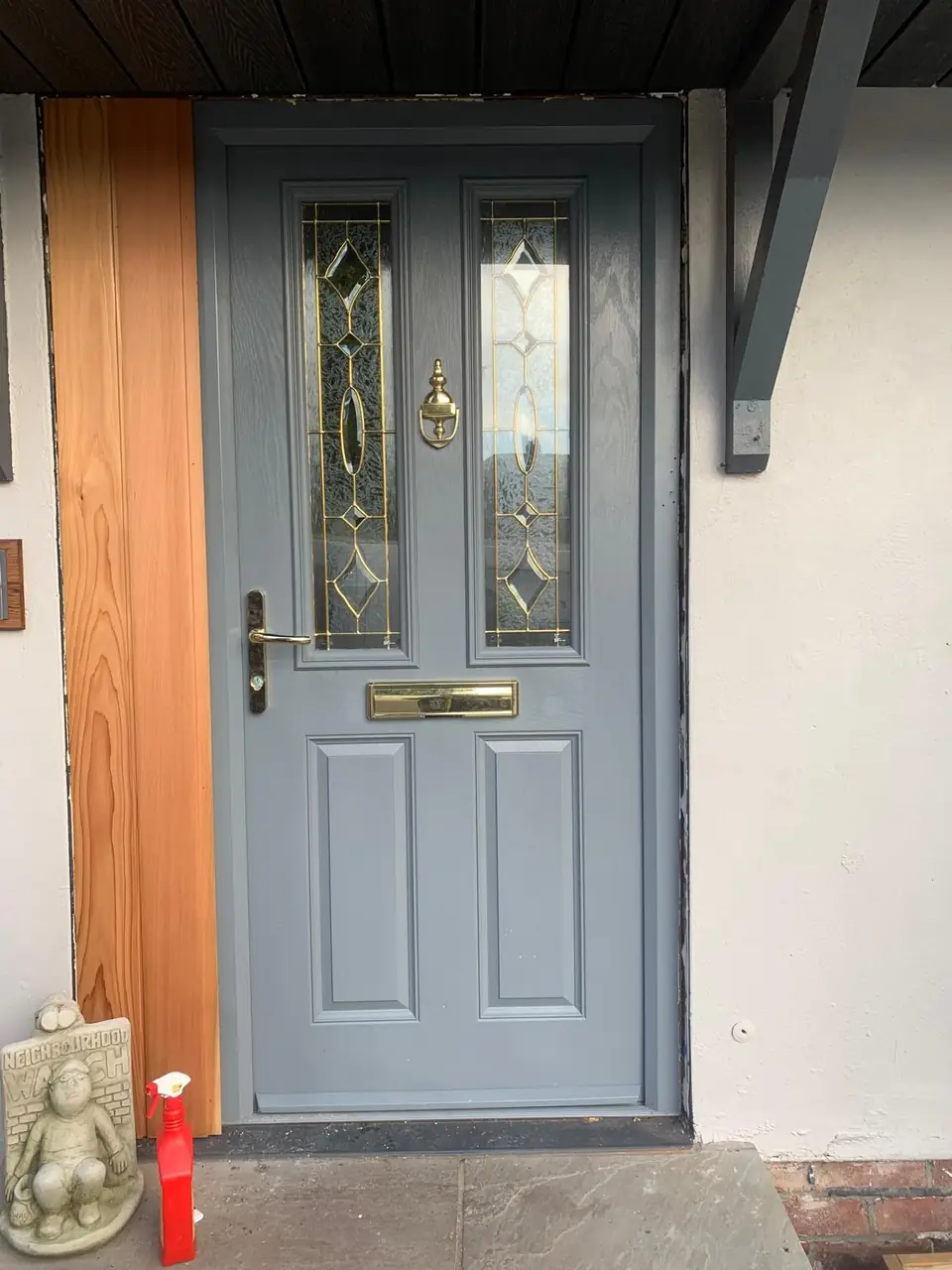 After: the same composite front door resprayed light grey, with brass door furniture