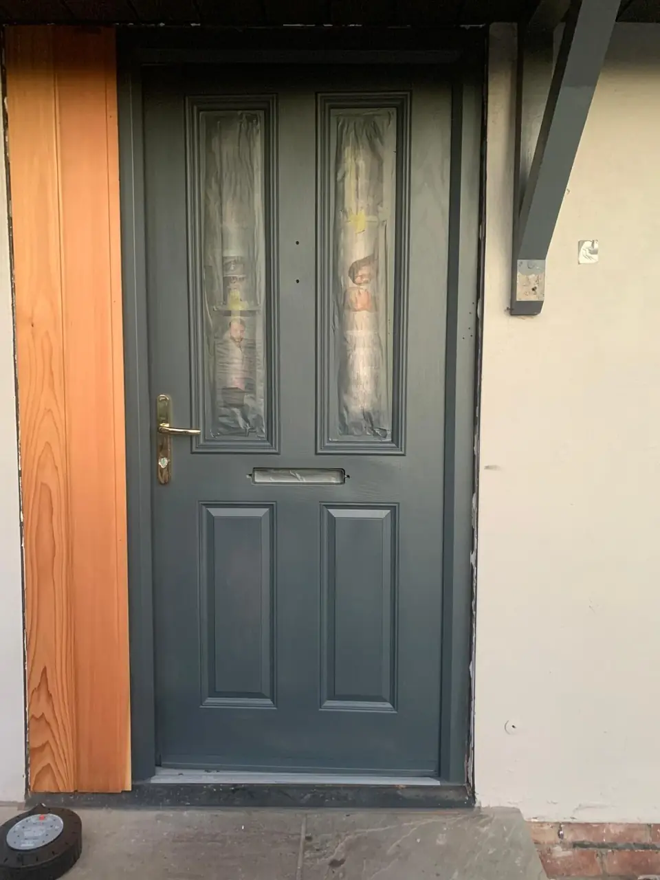 Before: composite front door in dark anthracite grey, with the glazing masked ready for spraying