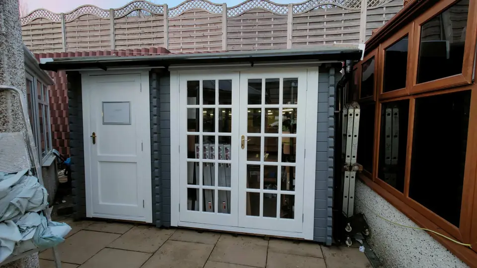 Garden room painted grey with white French doors and a matching side door