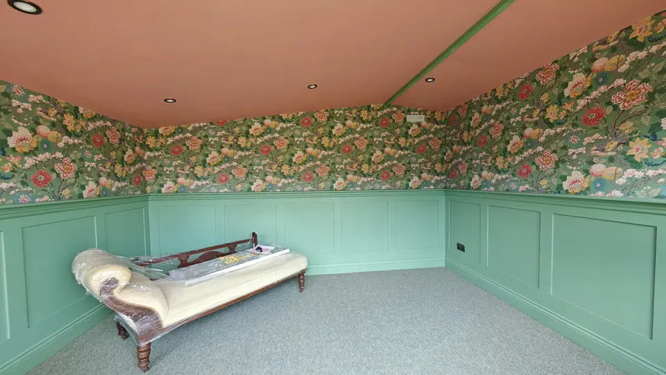 Sage panelling with floral wallpaper above