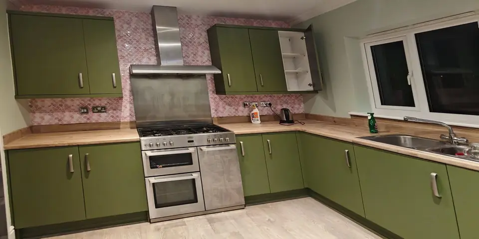After: the same kitchen in olive green with pink fish-scale tiles