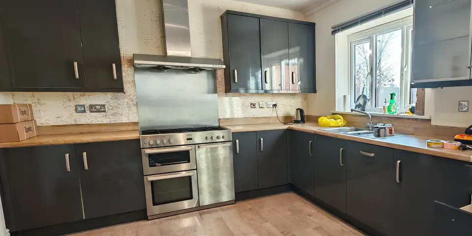 Before: dark grey gloss kitchen with a distressed wallpaper splashback