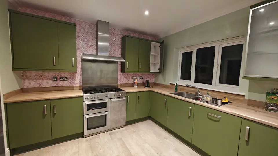Kitchen in olive green with a pink fish-scale tile splashback