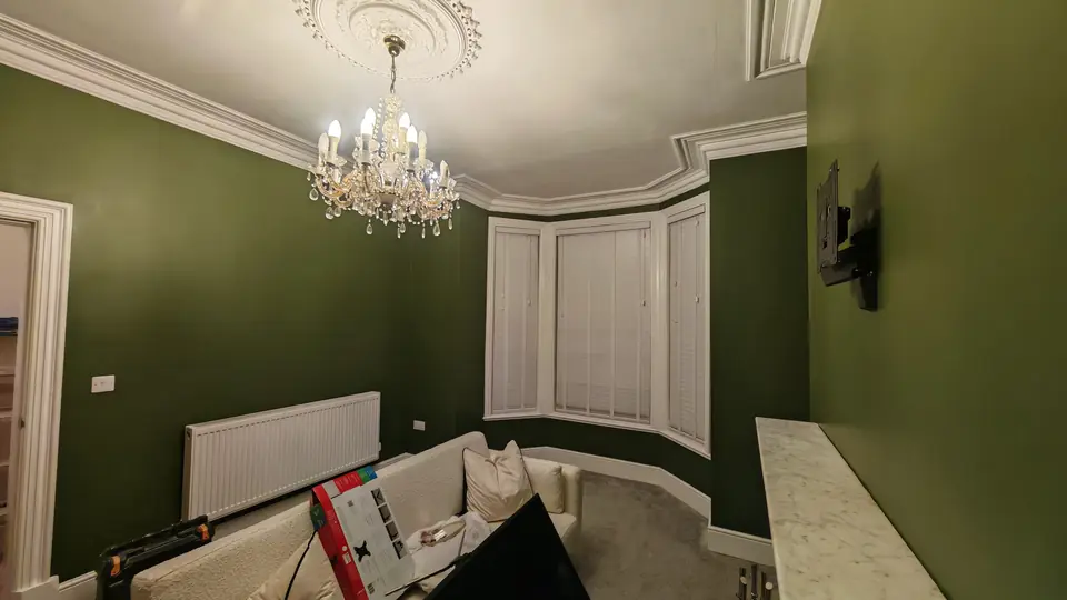 After: green lounge with bay window and chandelier