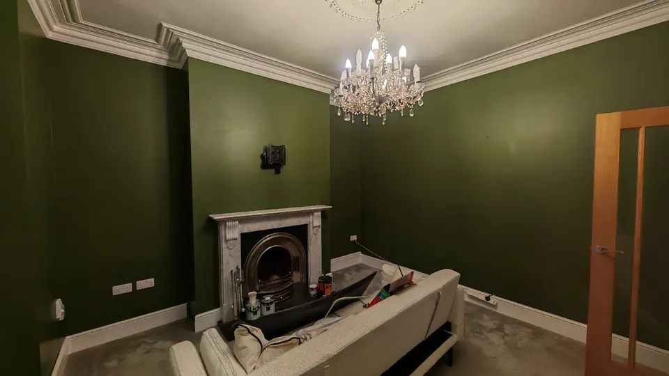 After: deep green lounge with white marble-effect fireplace