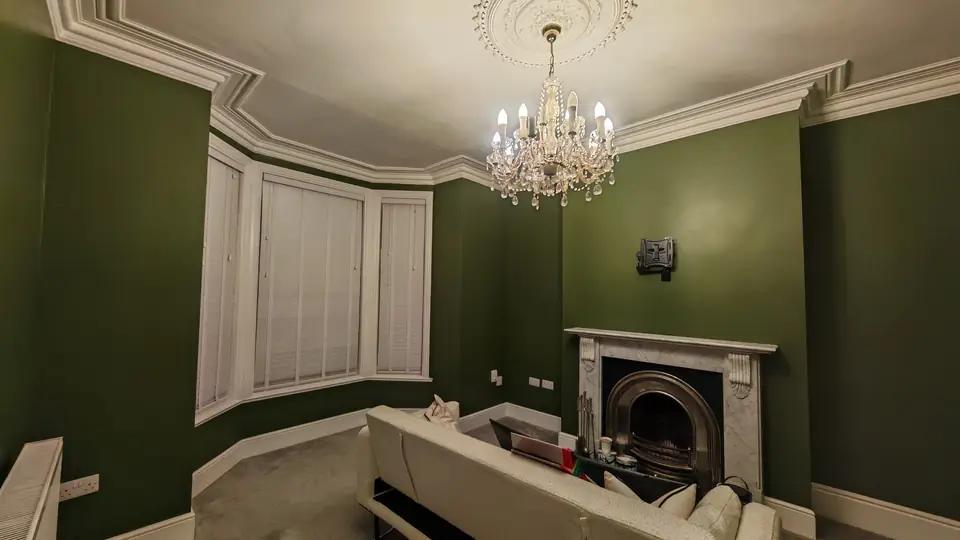 After: deep green living room, cornice and ceiling rose in white