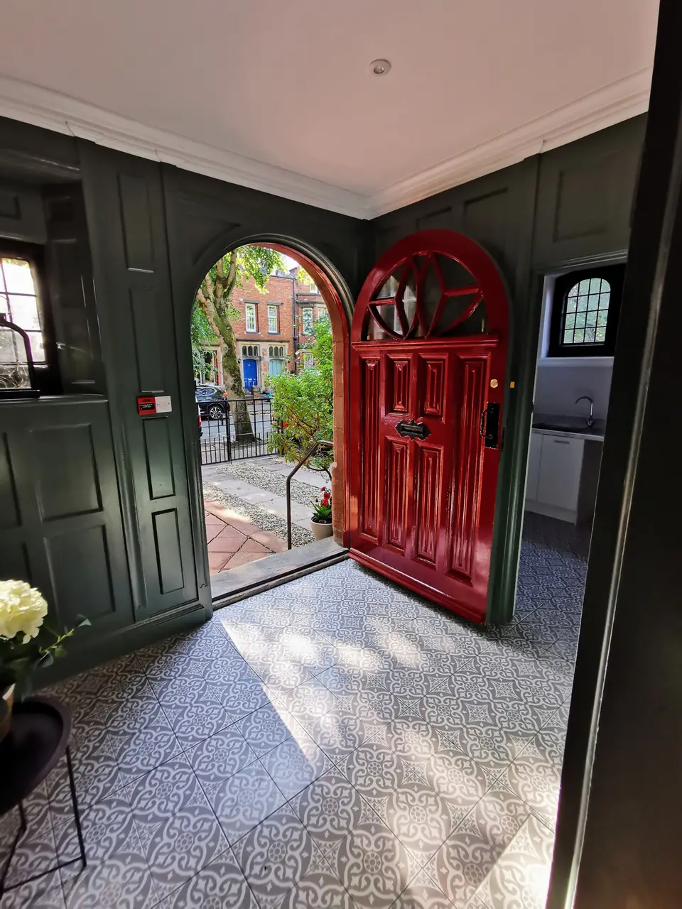 Porch painted dark green, framing a red arched front door
