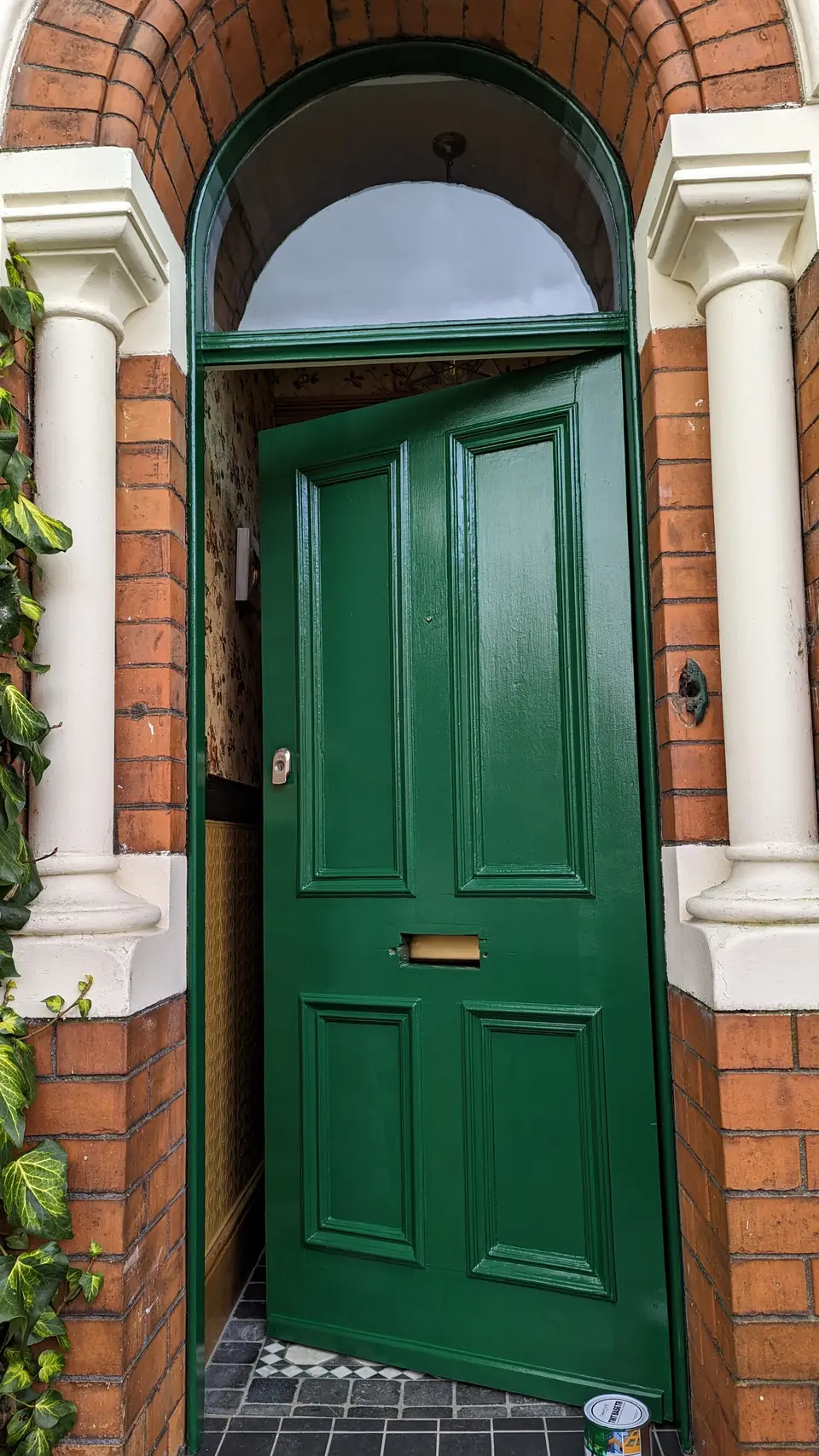 Victorian front door painted gloss racing green under a brick arch with cream pillars