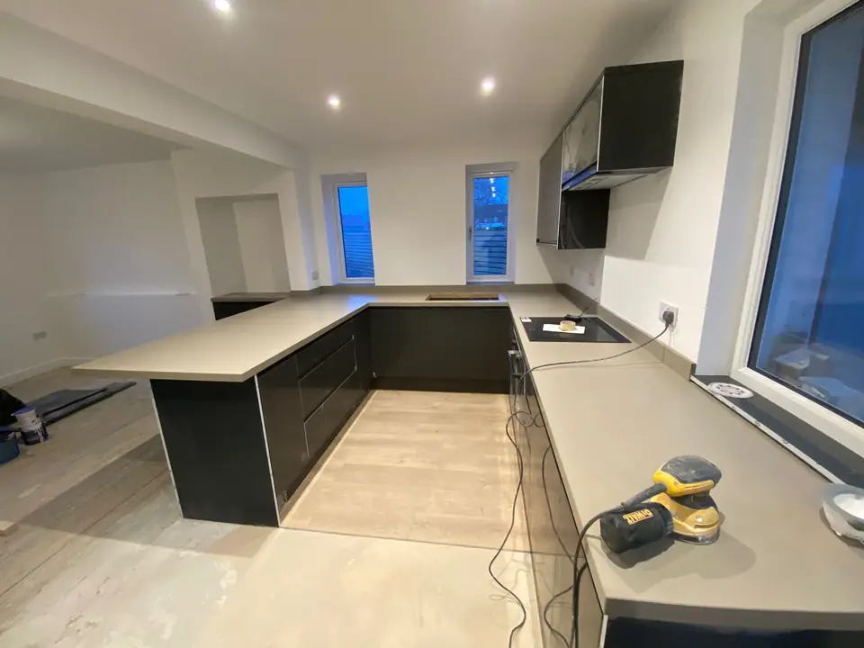 Grey handleless kitchen with a U-shaped island in a freshly painted room