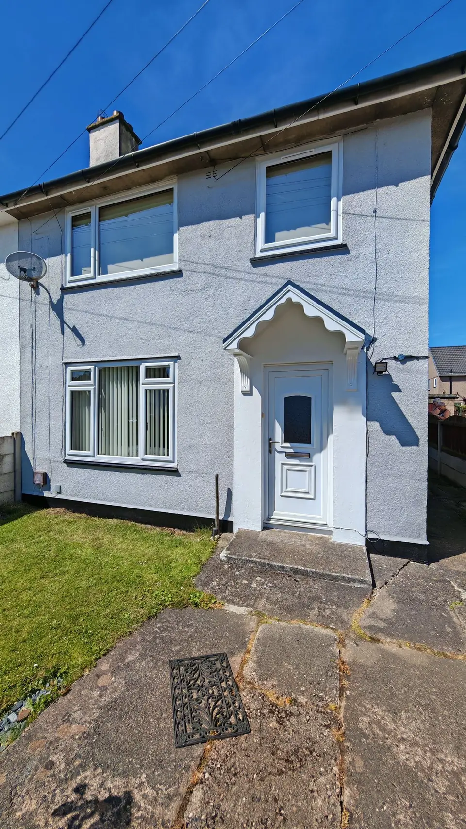 Pebbledash render repainted from cream to light grey, with a black plinth