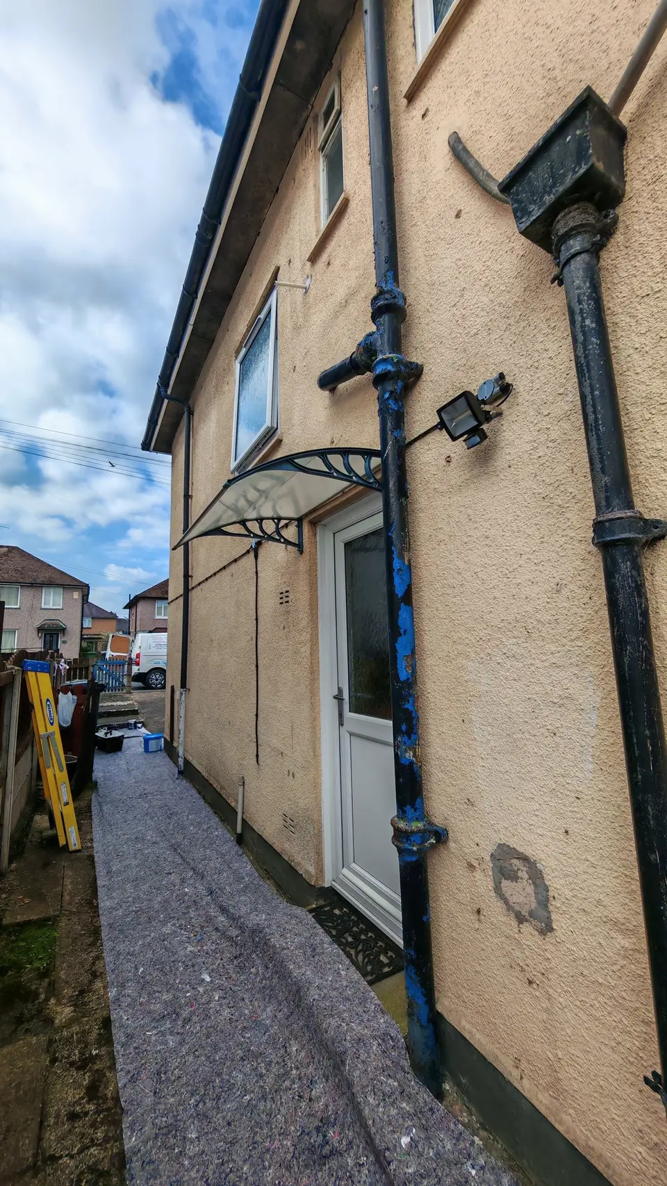 Before: side path with dust sheets down, cream walls and downpipes