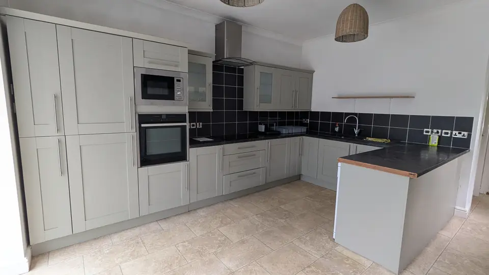 After: the same kitchen sprayed light grey with black worktops