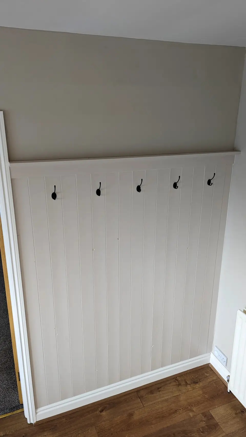 White tongue-and-groove panelling with coat hooks in a hallway