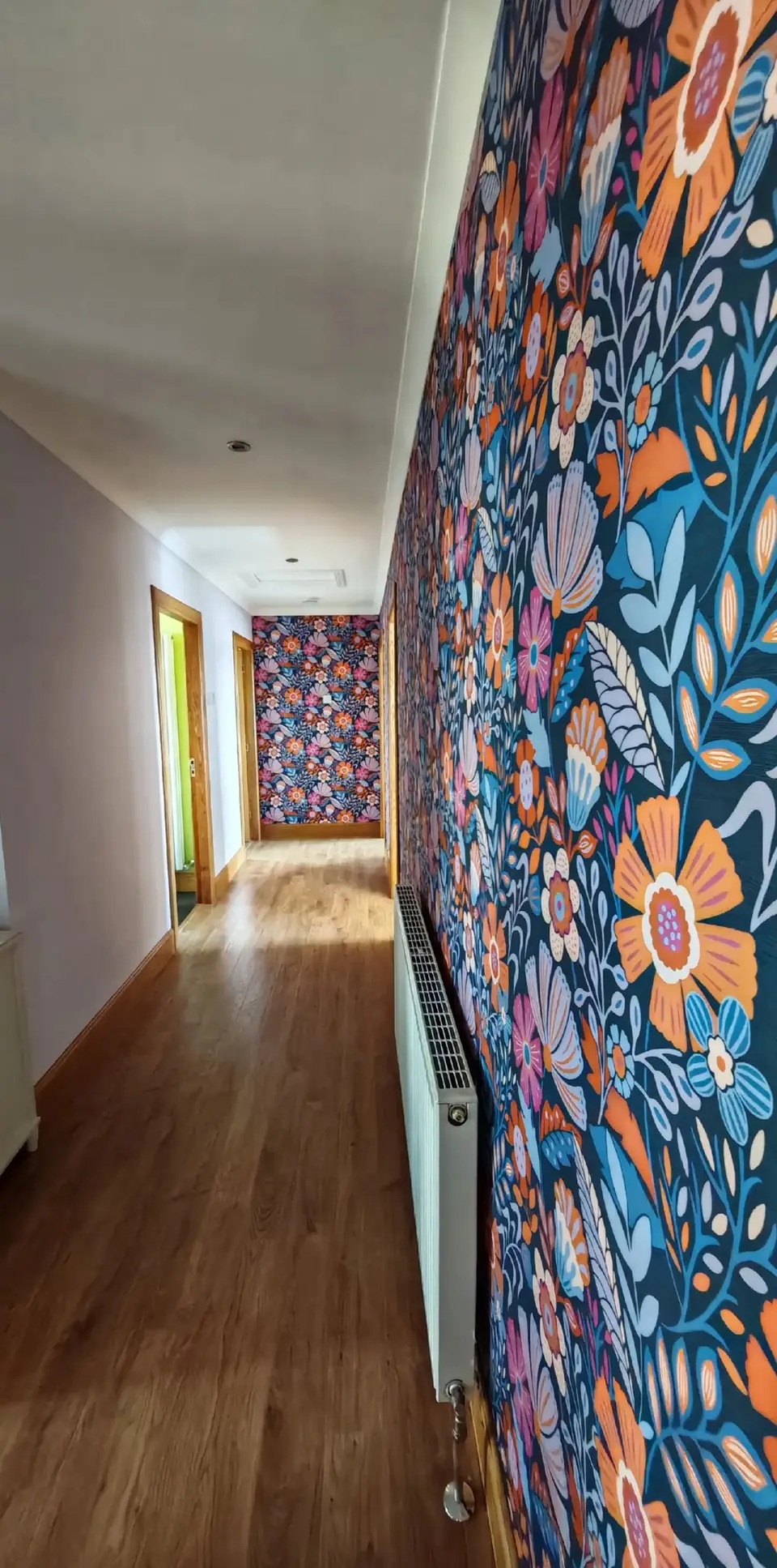 Long hallway hung in a bold navy and orange floral wallpaper