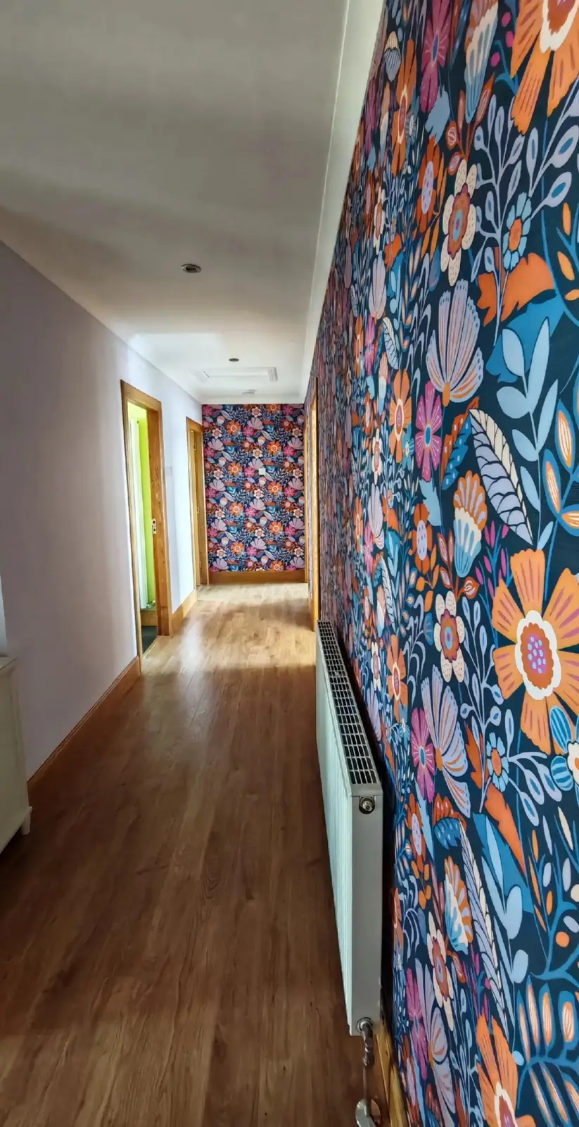 After: the same hallway hung in bold floral wallpaper