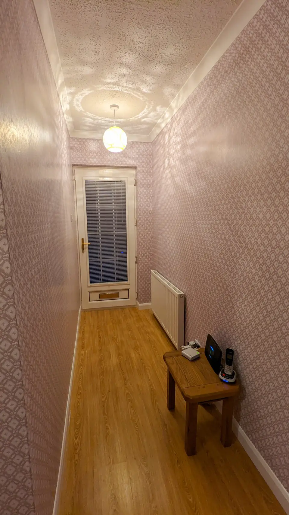 Long hallway finished in patterned wallpaper