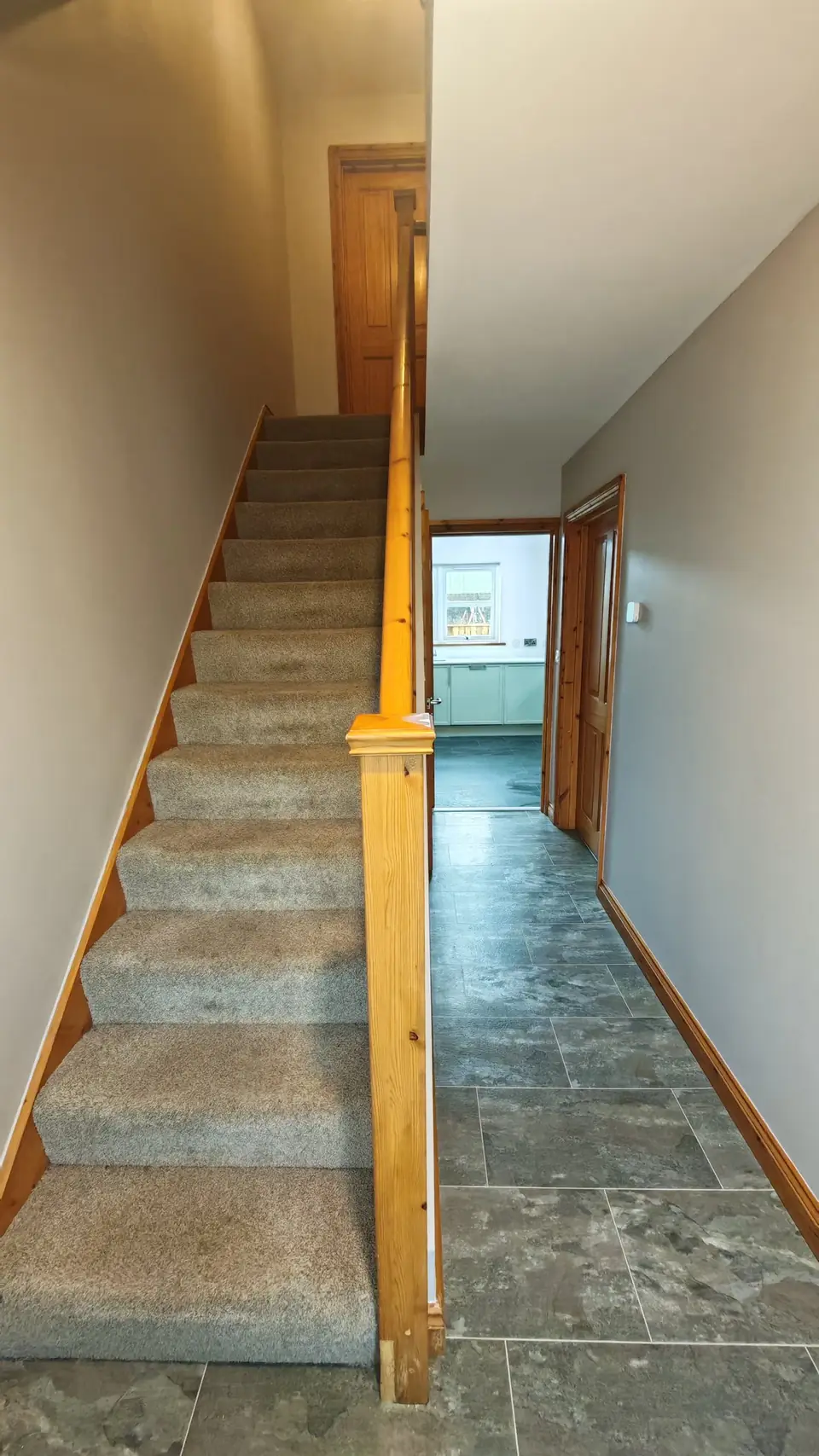 Hallway and stairs decorated in soft grey with oak doors and banister