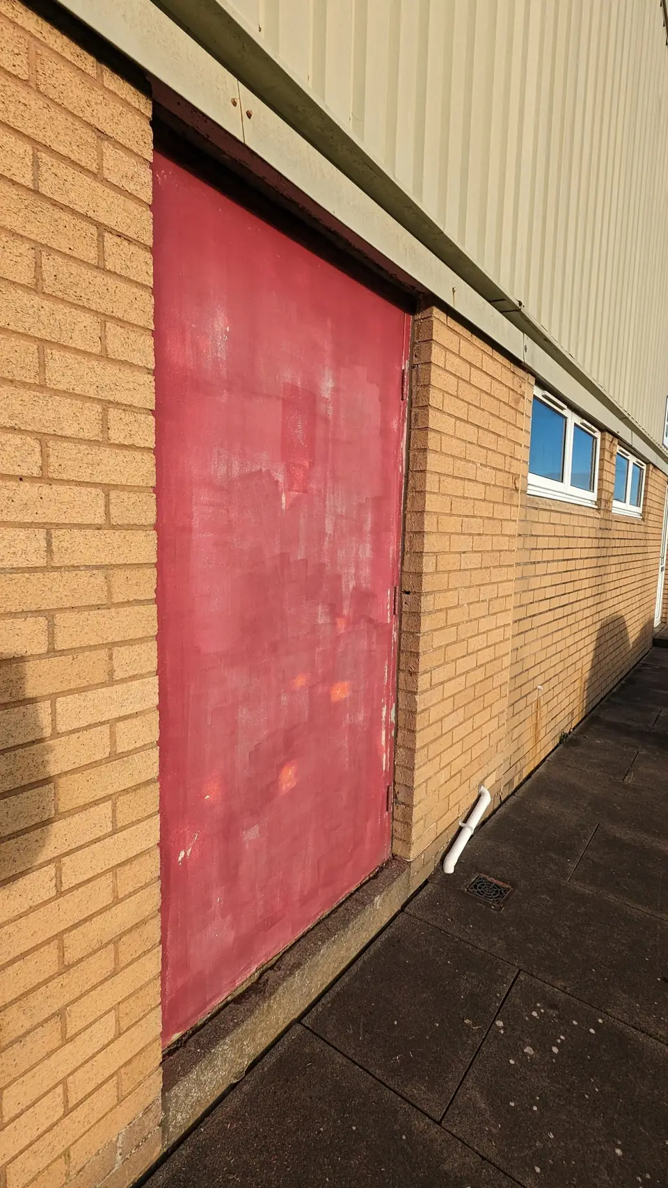Before: worn red steel door on a commercial unit
