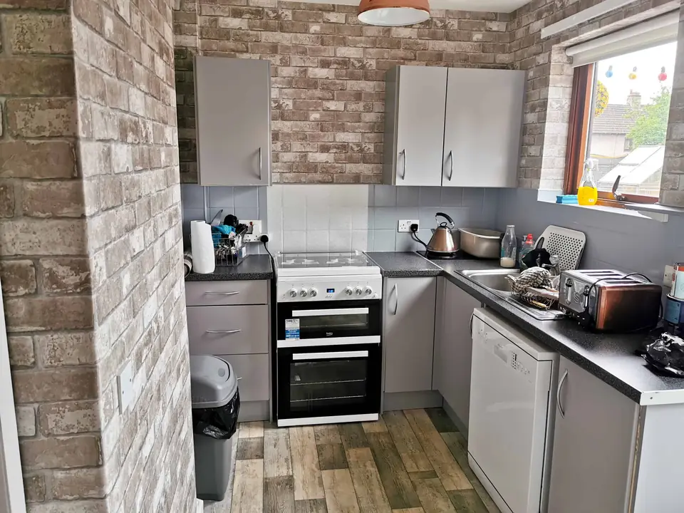 Kitchen with brick-effect feature wall and grey units