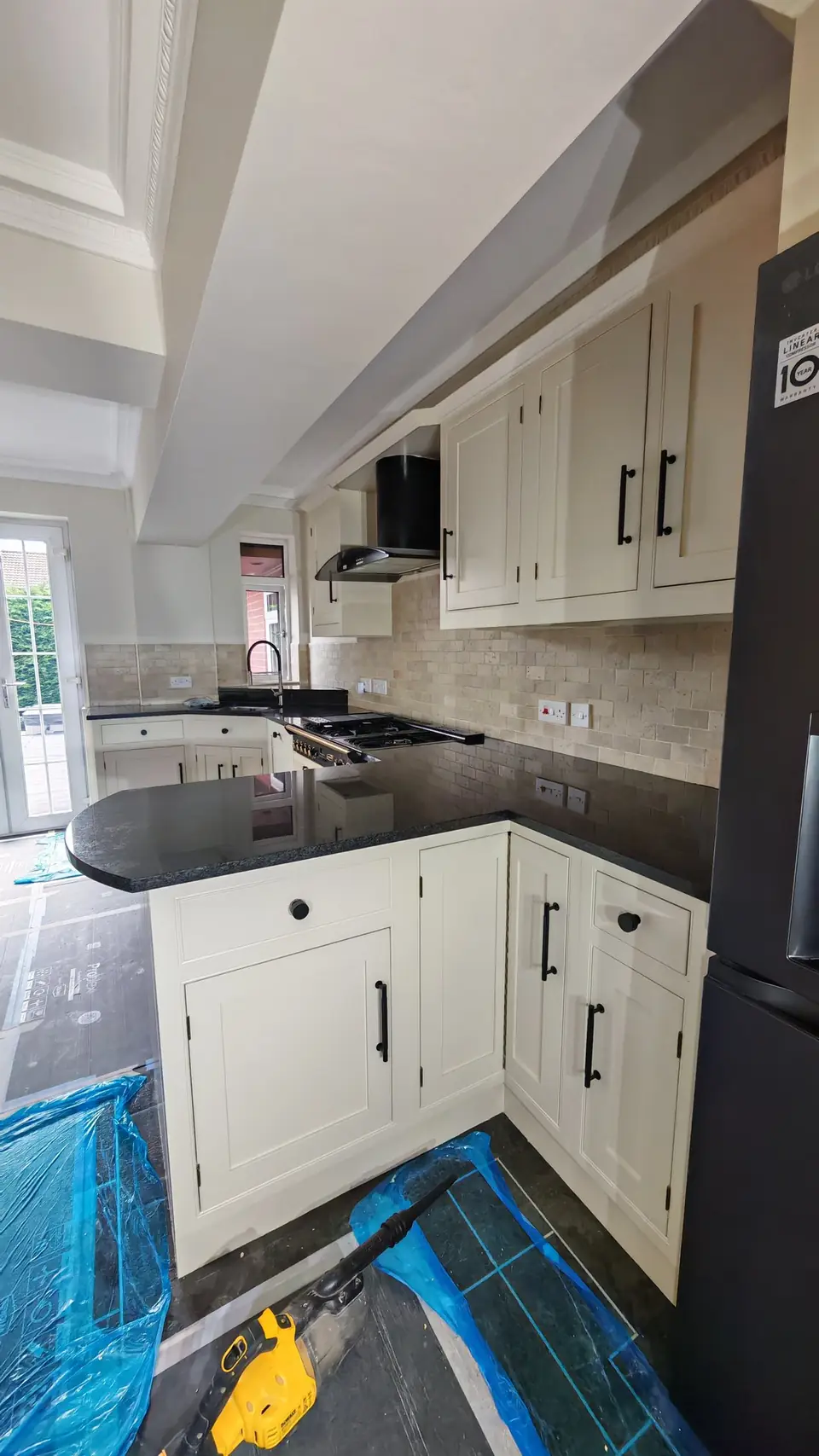Kitchen respray: cream in-frame units with black handles, black granite peninsula and travertine-style splashback