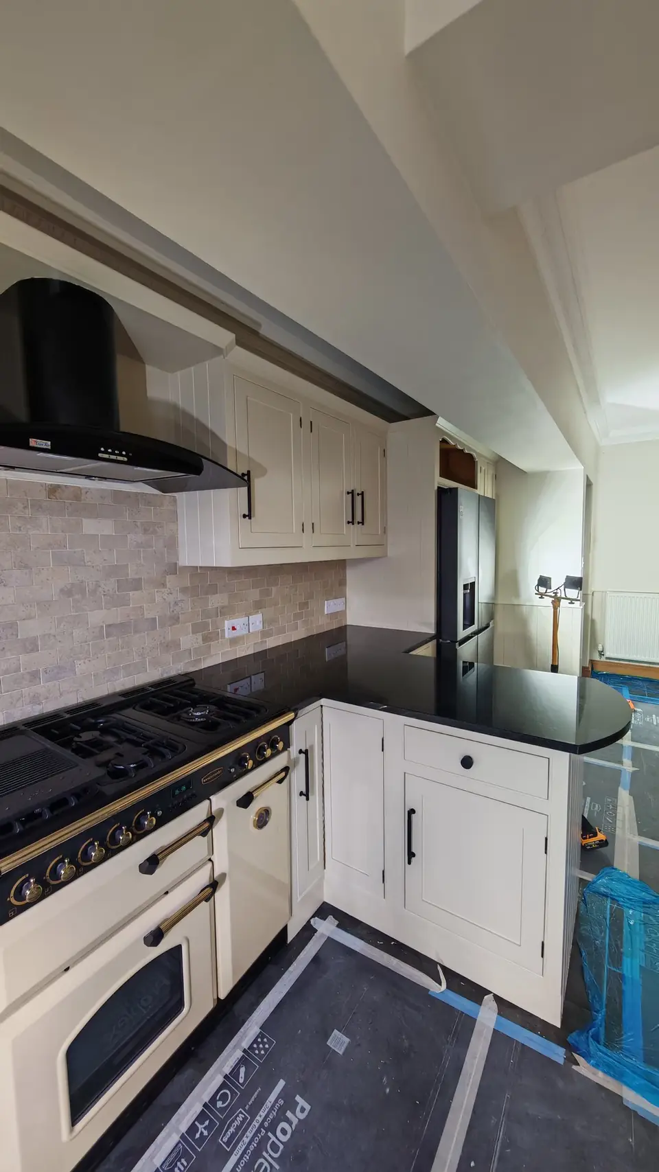 Kitchen respray: cream units around a range cooker and black extractor hood