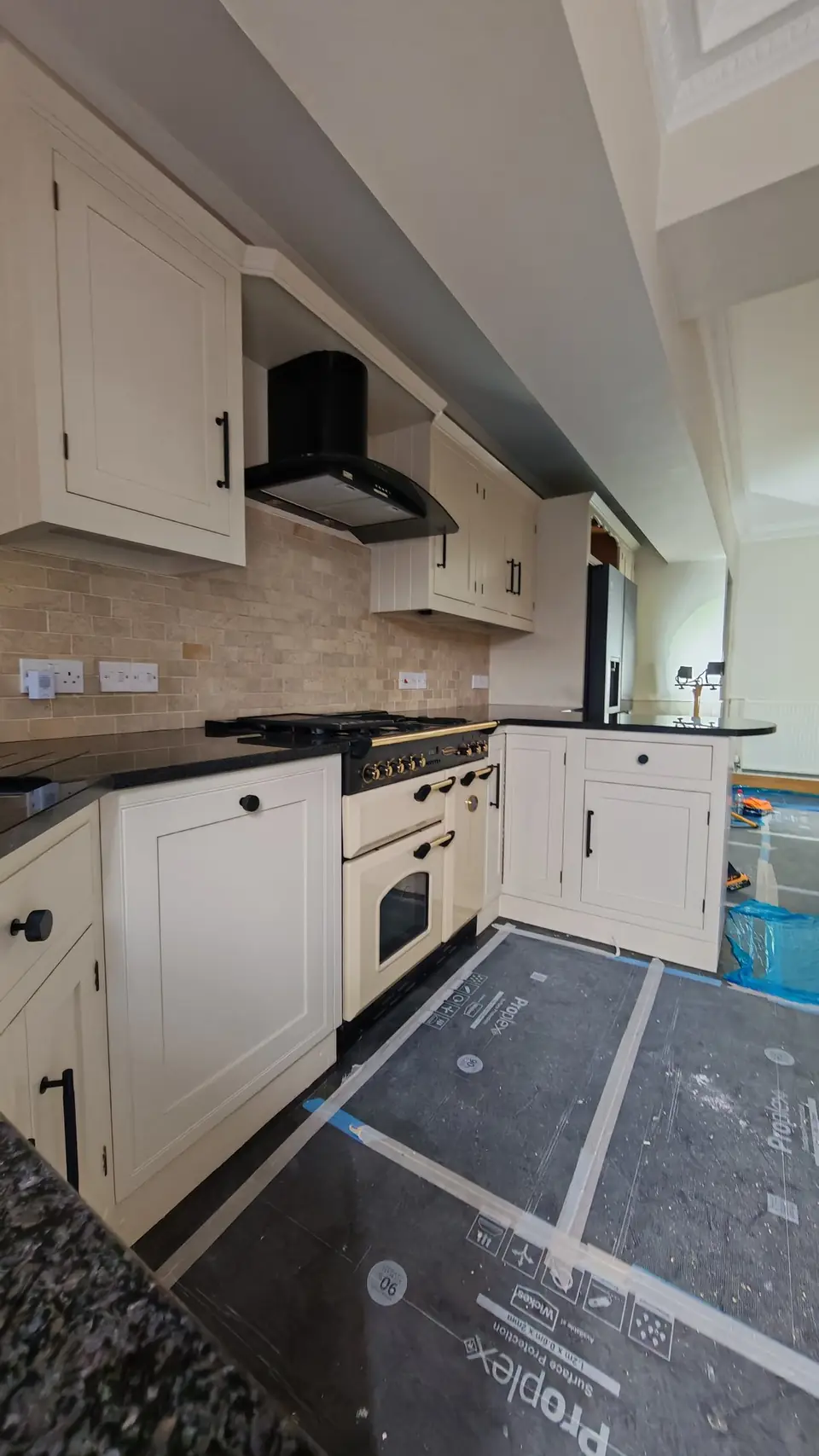 Kitchen respray: wide view of the cream kitchen with range cooker, floor protection still down