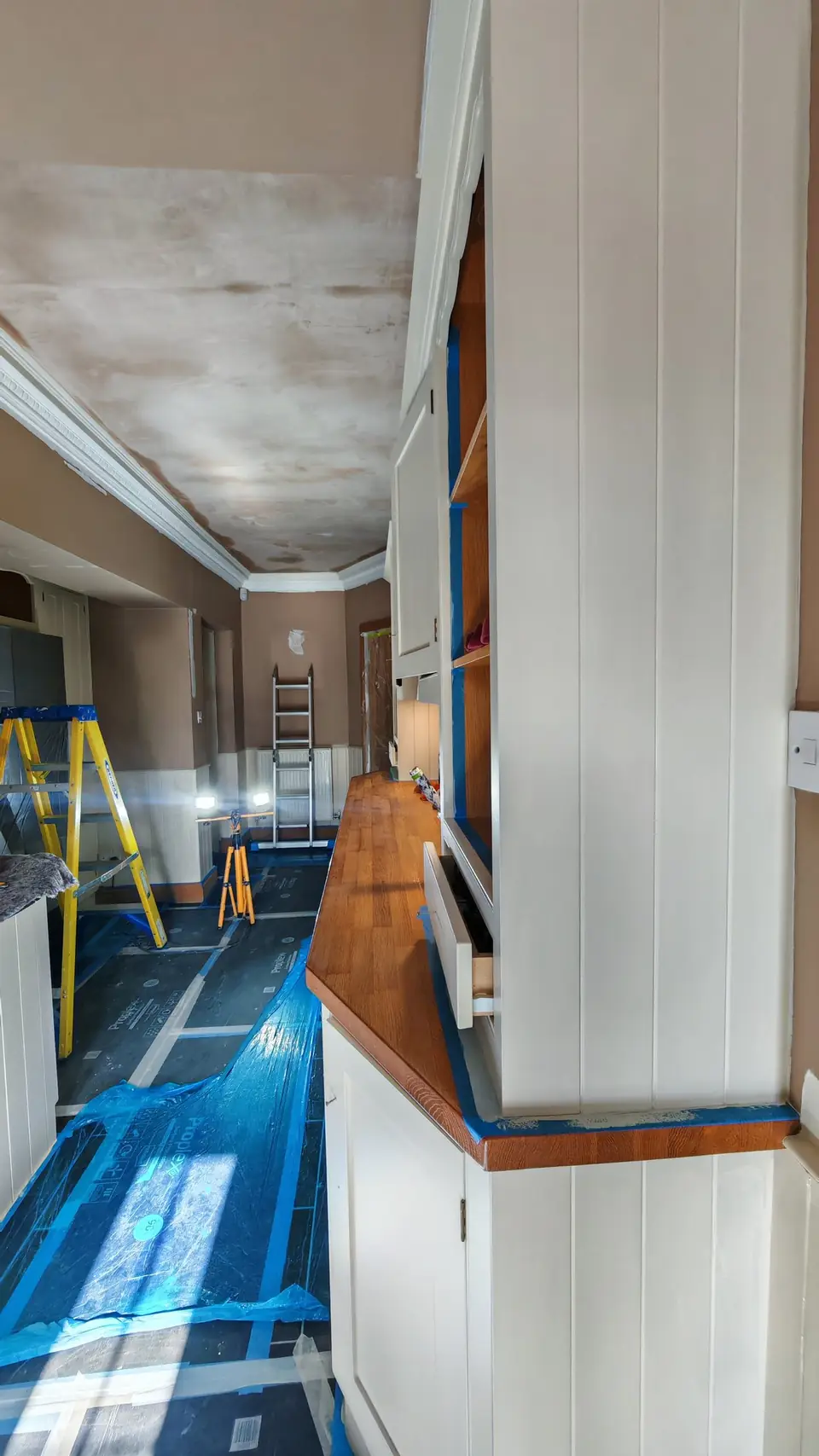 During: the dresser in undercoat with edges masked in blue tape, ceiling still bare plaster