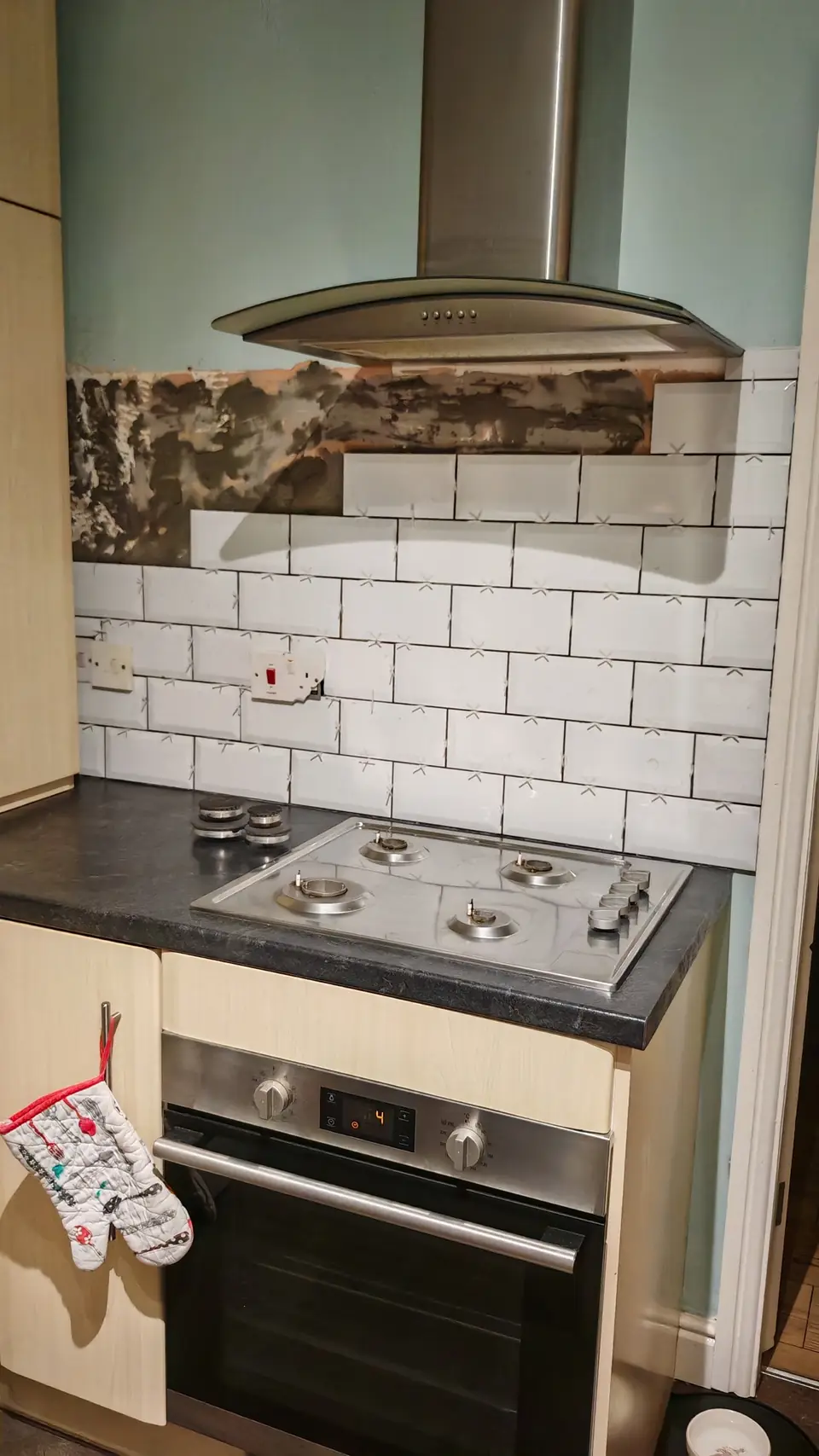 During: white metro tile splashback half tiled, old wall surface stripped above