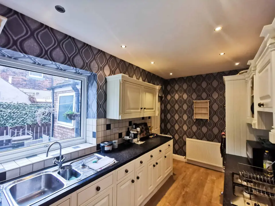Kitchen with cream units and geometric feature wallpaper