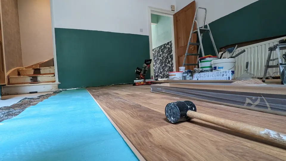 Laminate flooring being laid over underlay in a living room