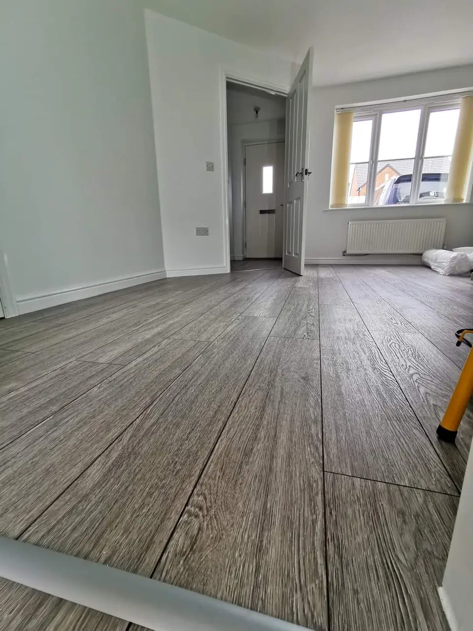 Grey oak-effect laminate flooring laid through a freshly painted room
